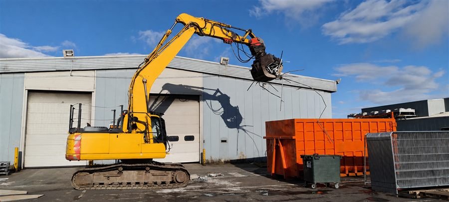 High-reach excavator carrying out mechanical demolition on site